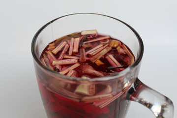Wedang Uwuh, or traditional tea from brewed sappanwood, ginger, lemongrass and cardamom. In transparent glass, isolated on white background