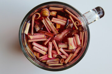 Wedang Uwuh, or traditional tea from brewed sappanwood, ginger, lemongrass and cardamom. In transparent glass, isolated on white background, flat lay or top view