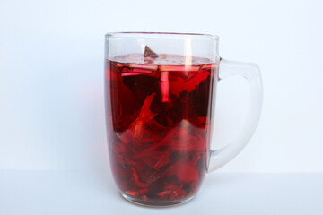 Wedang Uwuh, or traditional tea from brewed sappanwood, ginger, lemongrass and cardamom. In transparent glass, isolated on white background