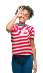 Young afro american woman over isolated background doing ok gesture with hand smiling, eye looking through fingers with happy face.