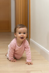 A smiling and happy baby crawls on the floor