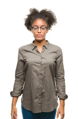 Young afro american woman wearing glasses over isolated background with serious expression on face. Simple and natural looking at the camera.