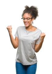 Young afro american woman wearing glasses over isolated background very happy and excited doing winner gesture with arms raised, smiling and screaming for success. Celebration concept.