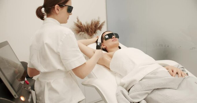 Beautician removes hair on beautiful female armpit using a laser. Hardware removal of hair on the legs in a beauty salon. Laser epilation cosmetology. hair removal procedure, Cosmetology clinic.