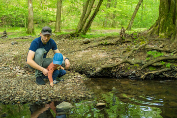 Dad with son toddler hiking together at sping forest near the river. 