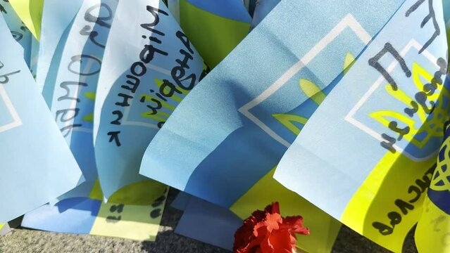 Many small flags of Ukraine with names of the dead war against russia. Memorial of the fallen soldiers, children, women in the center of Kyiv. Concept of tragedy and misfortune. Closeup