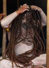 Portrait of an holy male naga sadhu baba with ash on his and long hairs wearning rudraksha necklace during the kumbh festival in India.