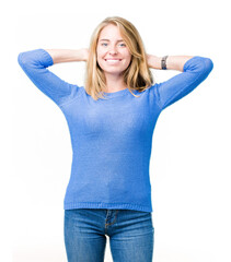 Fototapeta premium Beautiful young woman wearing blue sweater over isolated background Relaxing and stretching with arms and hands behind head and neck, smiling happy