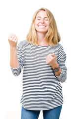 Beautiful young woman wearing stripes sweater over isolated background very happy and excited doing winner gesture with arms raised, smiling and screaming for success. Celebration concept.