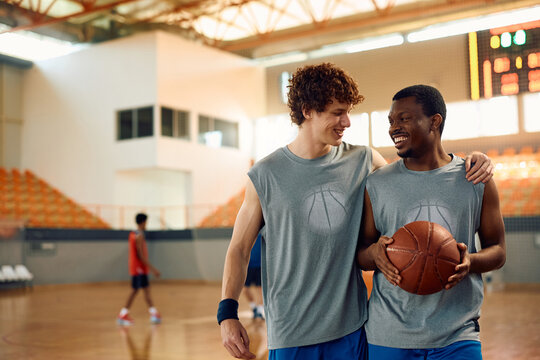 Happy basketball players talking during sports training at indoor court.