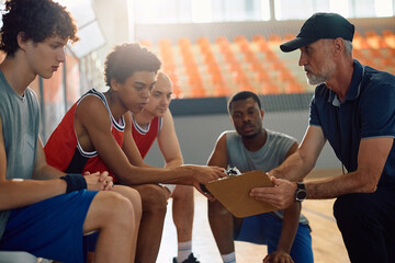 Basketball team and their coach going through game strategy on court.