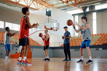 Group of basketball players having sports training with their coach on  court.