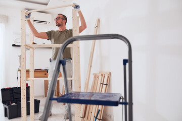 Naklejka premium Man assembling new wooden shelf and furniture in the apartment.