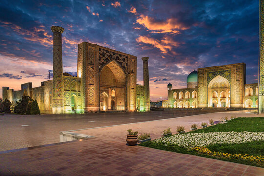 Planters in front of the Ulugh Beg madrasah and of the Tilla-Kari Mosque at the Registan Square at dusk in Samarkand, Uzbekistan