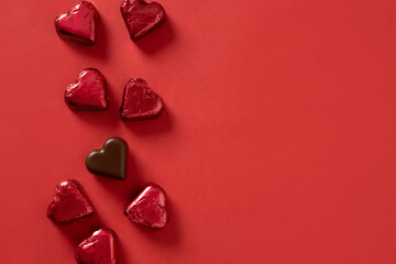 Romantic chocolate sweets as heart in red foil as frame on red background. Valentine's day greeting...