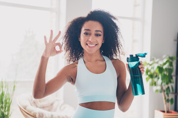 Photo of nice fit young woman hold bottle water show okay symbol sportswear training home gym...