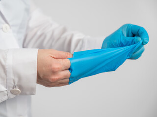 Doctor takes off latex gloves on a white background.