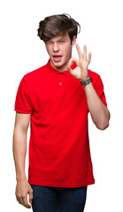 Young handsome man wearing red t-shirt over isolated background winking looking at the camera with...