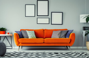 Beige walls with colorful posters and framed photographs in the style of retro interior of a modern living room with an orange sofa