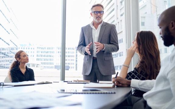 Businessman, mentor and meeting with team for presentation, corporate discussion or coaching at office. Man, CEO or executive talking to group of employees for business strategy or ideas at workplace