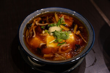 Aromatic Chinese Hot and Sour Soup Served in a Traditional Blue Bowl with Tofu and Mushroom Garnish