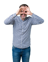 Handsome middle age elegant senior man wearing glasses over isolated background doing ok gesture like binoculars sticking tongue out, eyes looking through fingers. Crazy expression.