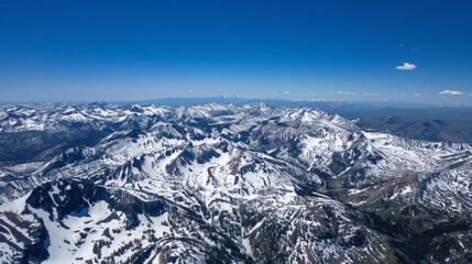 Fototapeta premium high-altitude drone photograph of snow-capped mountains under clear blue skies