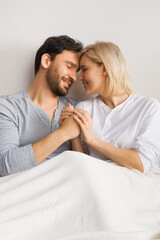 Fototapeta premium Image of closed eyes, holding hands man and woman, leaning their heads on each other, married inlove couple at bedroom, praying in home bed. Waiting child, planning pregnancy, plea concept.