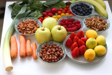 Apples, lemons, bananas, berries, carrots, leek, tomatoes, radishes, spinach and various nuts on white background. Healthy seasonal fruit and vegetable. Selective focus.