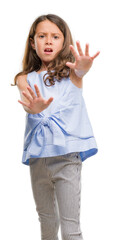 Brunette hispanic girl afraid and terrified with fear expression stop gesture with hands, shouting in shock. Panic concept.