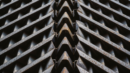 close-up view of textured steel metal panels made of interlocking wedges arranged in rows with visible weather corrosion and brown rust.