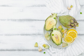 Fresh green artichokes cooking on wooden background. Traditional seasonal ingredients