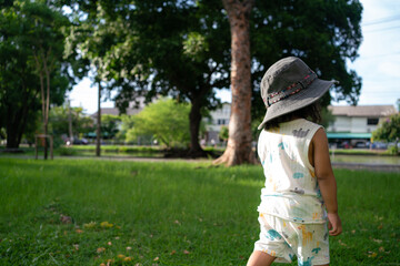 Toddler asian girl enjoying on green meadow grass sunset city park