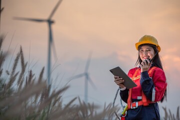 Woman engineer inspection posing check control wind power machine in wind energy factory at silhouette sunset. girl technician professional worker check wind power machine for maintenance turbine