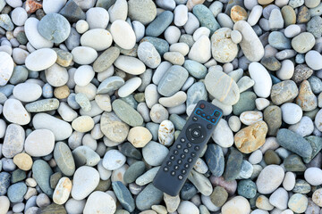 TV remote control on smooth sea pebbles
