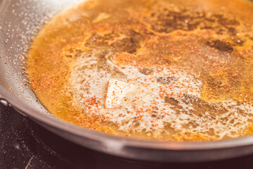 Making the sauce for crepe suzette, orange zest, juice and butter are fried for the sauce. Close-up.