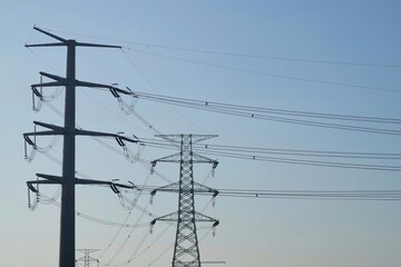 overhead electricity pylons. Lattice steel pylon. High voltage electricity tower. Silhouette High Voltage Electric Transportation.High voltage transmission pole against blue sky background.