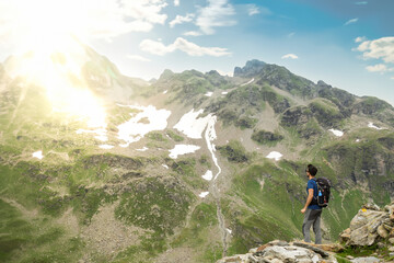 Outdoor sport theme: A hiker with a backpack enjoying the view of the mountains in the summer.