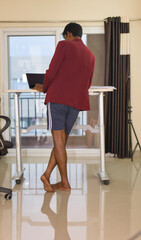 Rear view of a young man using laptop while standing in home work from home concept