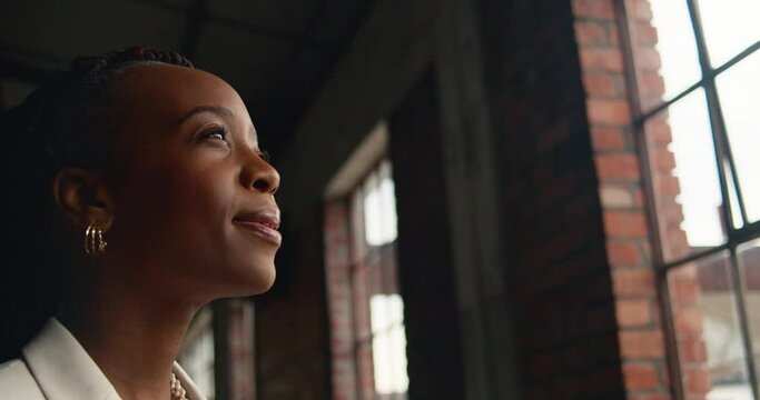 Professional African American Woman Gazing Out Window in Industrial Building