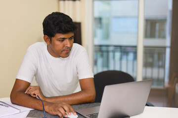 indian male freelancer working on his laptop computer at home office