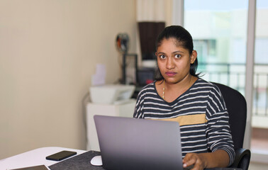 Portrait of a young Indian businesswoman using a laptop computer in an Home