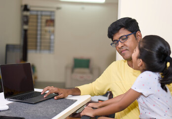 indian father and daughter using laptop computer in the living room at home
