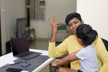 indian father teaching his daughter how to use a computer at home