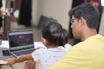 Father and daughter using laptop computer at home Family and technology concept
