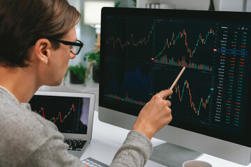 Smart stock investors pointing interesting market stock exchange on pc with laptop screen....