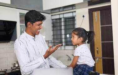 Fototapeta premium indian father helping his daughter with homework in the kitchen at home
