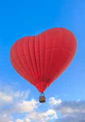 Heart shaped balloon with basket on blue sky. Red color hot air balloon for recreation travel, flight adventu