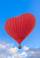 Naklejka premium Heart shaped balloon with basket on blue sky. Red color hot air balloon for recreation travel, flight adventu