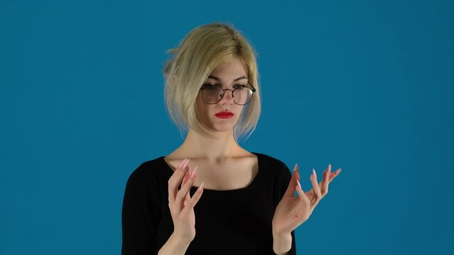 Businesswoman takes off glasses with shocked face on blue background. Female manager slaps palm to forehead with anger and frustration